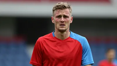 Mid-30s GIF Sundsvall midfielder, lean build, shoulders hunched, head-and-shoulders shot, face flushed with...