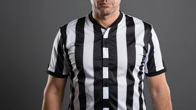 A tight waist-up shot of a middle-aged man with a stern expression, wearing a black and white striped shirt with a...