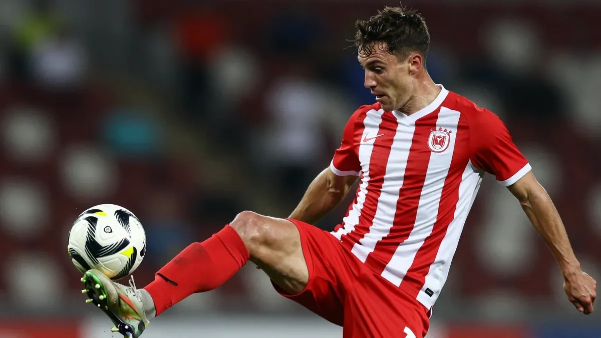 A tight action shot of a young, muscular striker in a red and white striped shirt, mid-kick, about to strike the ball...