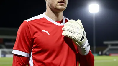 A photorealistic image of an anonymous GIF Sundsvall player in a red and white jersey, with a white goalkeeper's glove...
